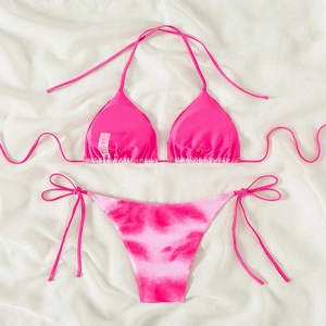 Detailed flat lay of pink halter bikini top and side-tie tie-dye bottoms on white fabric