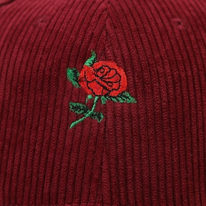 Detailed close-up of rose flower embroidery on textured corduroy baseball cap fabric