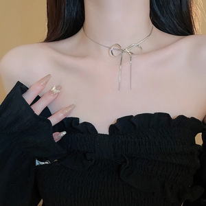 Close-up of minimalist silver metallic bow necklace worn by a model for elegant look