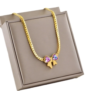 Golden bow pendant necklace with purple heart gems displayed on a jewelry box