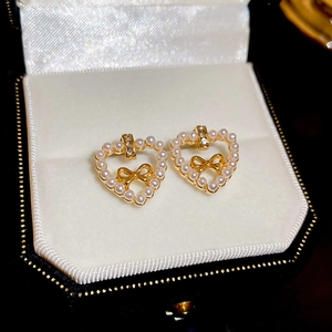 Macro shot of gold heart earrings with pearls and rhinestones in a black jewelry box