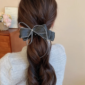 Detail of elegant black velvet bow hair claw with silver glitter edges on back view