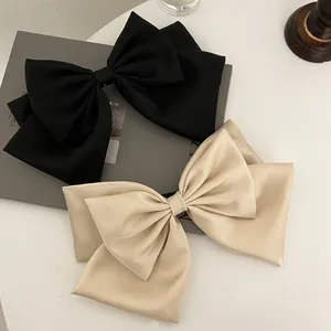 Detail of elegant double-layered oversized bows in matte black and beige satin fabric