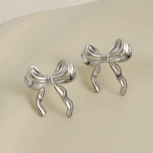Macro shot of silver bow stud earrings with detailed metallic texture and minimal design