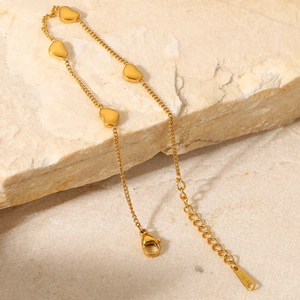 Dettaglio di ciondoli a cuore in oro 18K su catena in acciaio inossidabile e pietra