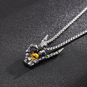 Macro shot of silver dragon claw pendant holding a yellow tiger eye stone on a chain