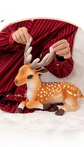 Detail of soft plush spotted reindeer toy being held on a bed for kids comfort