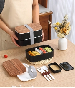Double-layer bento box with wood-texture lid and full cutlery set in a cozy home setting
