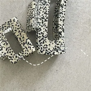 Detail view of two rectangular hair claws with minimalist black and white spotted patterns