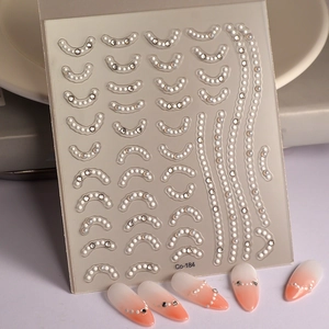 Dettaglio adesivi per unghie 5D con perle bianche e strass su unghie color arancio