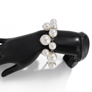 Detail of multi-size white pearls on a black hand model with a silver metal clasp