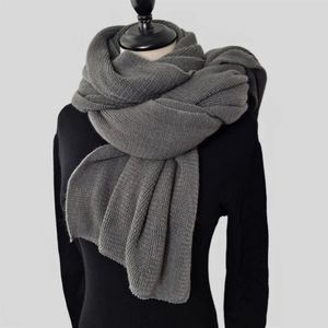 Detailed texture of thick dark grey knitted winter scarf with soft fringe edges