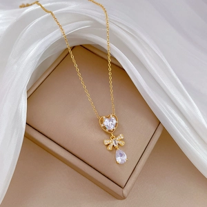Macro detail of golden necklace with heart and butterfly zircon pendants on silk