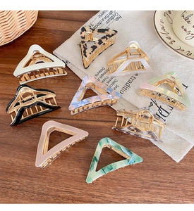 Flat lay of hollow triangle hair claws in multiple colors on a wooden background