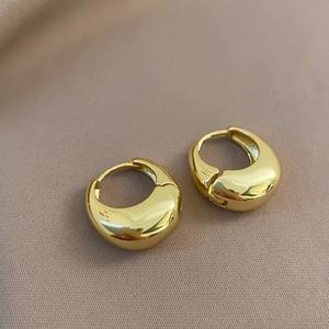 Detailed view of gold plated teardrop huggie earrings with a polished mirror finish surface