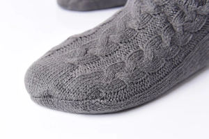 Close-up of grey cable knit slipper socks featuring detailed warm fleece texture