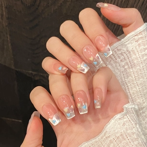 Macro detail of clear coffin press-on nails with colorful 3D heart charms and glossy finish