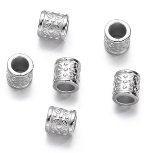 Macro shot of silver hollow cylindrical beads with intricate vintage floral carvings