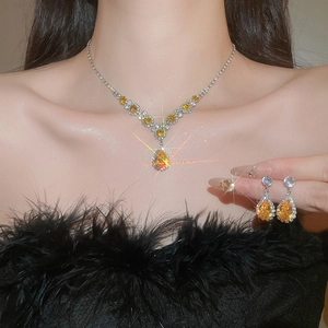 Macro shot of silver necklace and earrings with yellow pear-cut zircon crystals