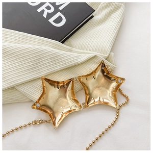 Detailed macro view of the shiny gold star-shaped metal mini bag with magnetic closure