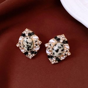 Détail de boucles d'oreilles vintage en forme de losange avec monture dorée et pierre ovale