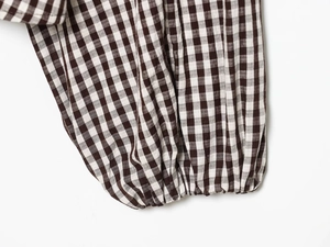 Detail of coffee and white gingham shirt featuring elastic pleated cuff craftsmanship
