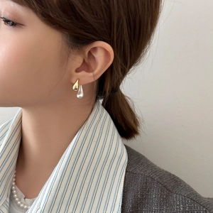 Bicolor teardrop stud earrings in gold and silver finish worn by a model in casual style