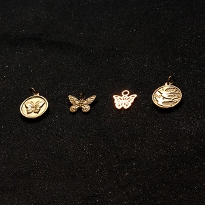 Close-up of golden butterfly and swallow charms with intricate vintage embossed details