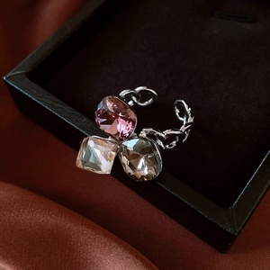 Détail d'une bague chaîne réglable avec pierres carrées roses, blanches et grises