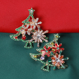 Detail of colorful crystal rhinestones on gold Christmas tree brooches with festive background