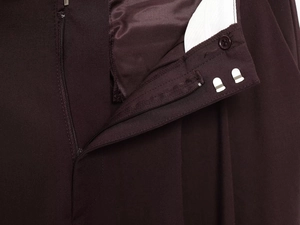 Macro view of women's dark brown trousers featuring a metal hook, zipper, and button closure