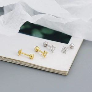 Macro detail of gold and silver eight-pointed star stud earrings with zircon inlay