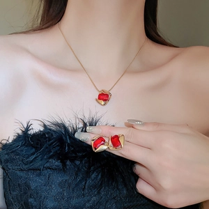 Detail view of retro stainless steel jewelry set with red gems worn by a female model