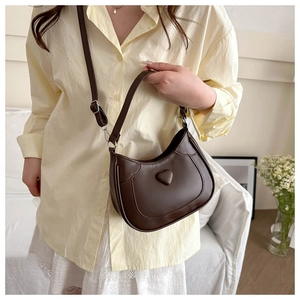 Detailed close-up of brown PU leather crescent bag with embossed heart decor and strap