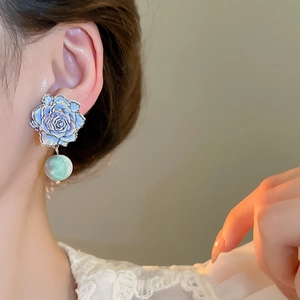 Detail of blue flower earrings with green beads on a model, elegant vintage style