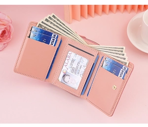 Macro view of a pink tri-fold leather wallet showing internal card slots and ID window