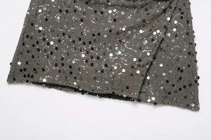 Dettaglio macro del tessuto verde oliva con paillettes argento su una minigonna chic