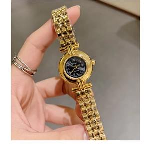 Macro detail of gold steel strap watch with black roman dial and quartz movement