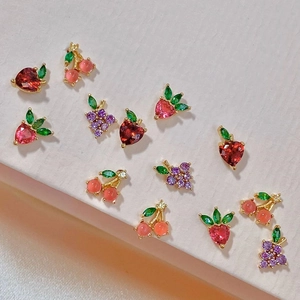 Detail of fruit shaped earrings with colorful zircons like strawberry and cherry