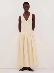 Gros plan sur la taille nouée et le col en V d'une robe longue beige sans manches