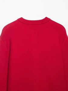 Dettaglio di un maglione rosso a maglia che mostra il girocollo e la trama fine
