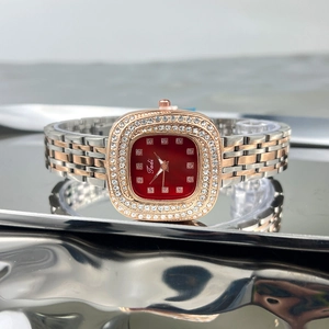 Close-up of a luxury square green watch with a red dial and diamond-encrusted bezel