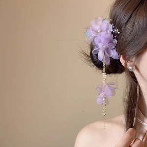 Détail de pince à cheveux fleur en tissu violet avec glands dorés et perles sur modèle