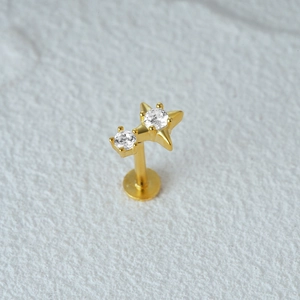 Detailed macro view of gold star piercing stud with two clear round gemstones