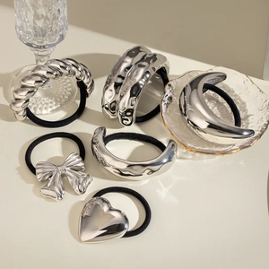 Detail view of various silver-tone metal charms on black elastic hair ties set
