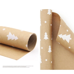 Close-up of kraft wrapping paper rolls featuring white Christmas tree and snowflake patterns