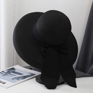 Detalle de sombrero de paja negro con lazo de gasa vintage y cintas largas elegantes