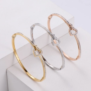 Close-up of interlocking heart bangles in gold, silver, and rose gold with white cubic zirconia