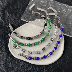 Detail of beaded bracelets set in blue, emerald and white with silver charms