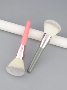 Detail of two large fluffy powder brushes with pink and grey handles on a minimalist background